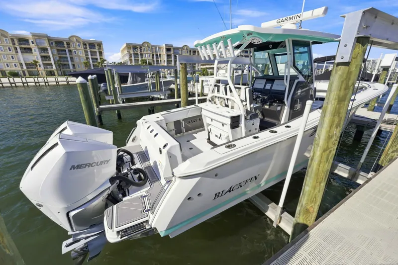 Slide: The Image of 2021 Blackfin 272 CC boat docked with Mercury engine, waterfront buildings in background. - 25