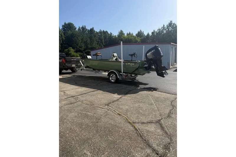The Image of 2024 SeaArk Flex 19 boat on trailer with Suzuki outboard motor, parked outdoors. - 0