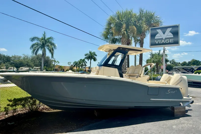The Image of 2027 Scout 260 LXF boat displayed outdoors with palm trees and dealership sign. - 0