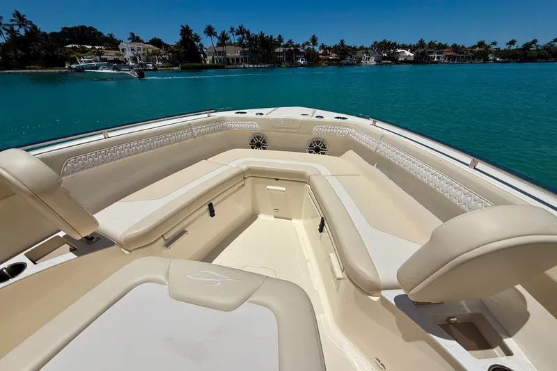 Slide: The Image of 2027 Scout 260 LXF boat interior with luxurious seating, docked by turquoise waters. - 17
