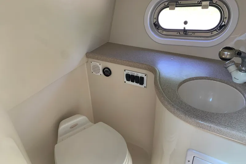 Slide: The Image of 2005 Four Winns 328 Vista boat bathroom with sink, toilet, and porthole window. - 27
