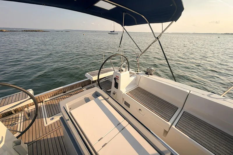 Slide: The Image of 2021 Beneteau Oceanis 41.1 yacht deck with dual steering wheels, overlooking calm sea. - 17