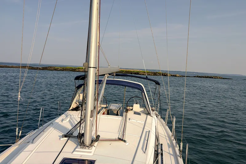Slide: The Image of 2021 Beneteau Oceanis 41.1 sailboat cruising on calm waters near rocky shoreline. - 10