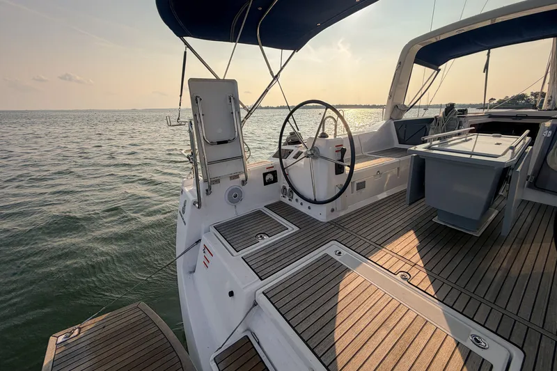 Slide: The Image of 2021 Beneteau Oceanis 41.1 yacht deck with steering wheel, sunset view over calm waters. - 22