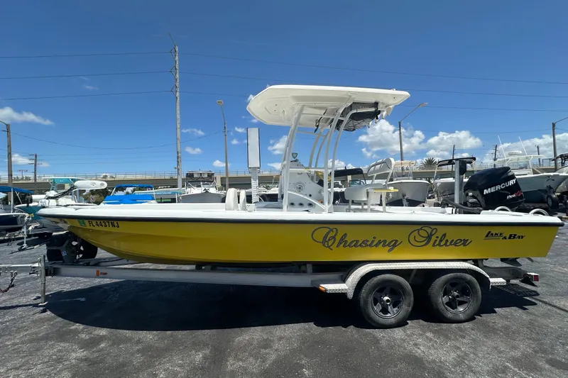 Slide: The Image of 2007 Lake & Bay Backwater 24 boat, yellow hull, on trailer, clear sky background. - 1