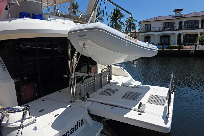Slide: The Image of Aquila 48 yacht with a dinghy on davits, docked by waterfront homes, 2016 model. - 32