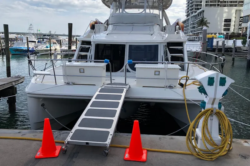 Slide: The Image of Aquila 48 yacht docked at marina, featuring boarding ramp and utility connections, 2016 model. - 15