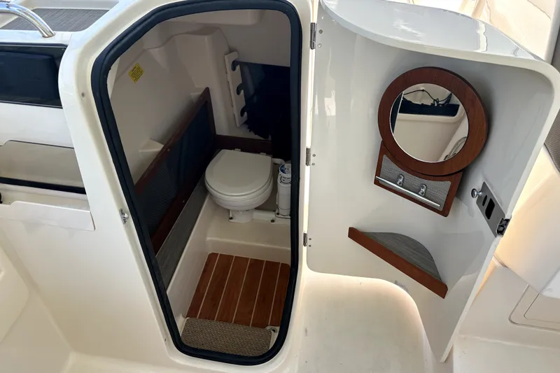 Slide: The Image of 2021 Grady-White Freedom 275 boat interior with compact bathroom and wooden accents. - 16