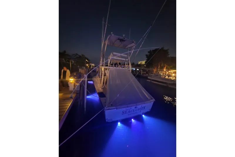 Slide: The Image of 2001 Pursuit 3000 Offshore boat docked at night with blue underwater lights. - 6