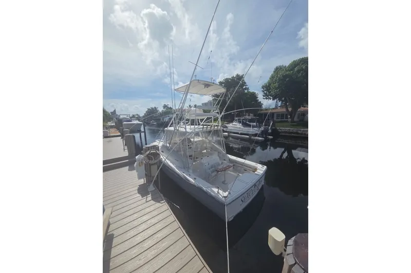 Slide: The Image of 2001 Pursuit 3000 Offshore boat docked at a marina under a cloudy sky. - 2