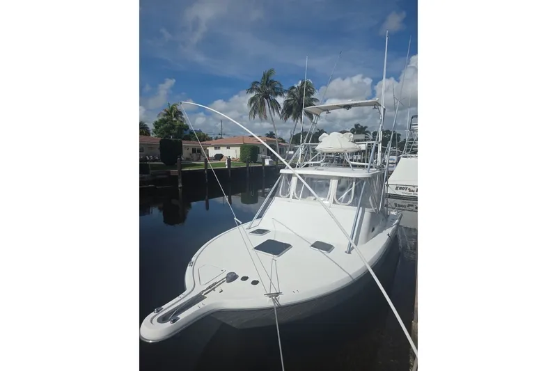 The Image of 2001 Pursuit 3000 Offshore boat docked under clear skies with palm trees. - 0