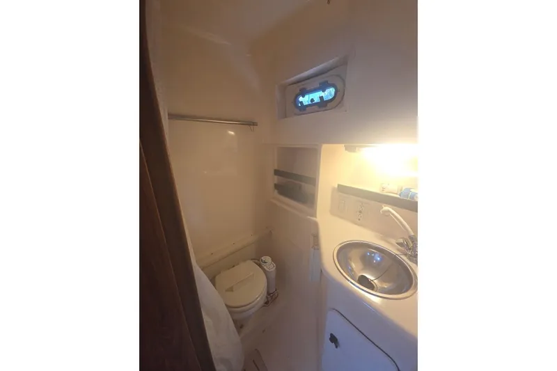 Slide: The Image of Compact bathroom in a 2001 Pursuit 3000 Offshore boat, featuring a toilet and sink. - 15