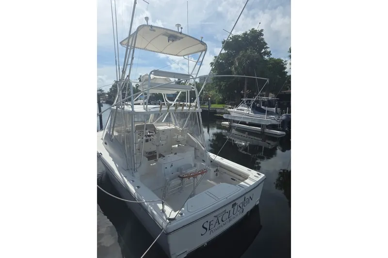 Slide: The Image of 2001 Pursuit 3000 Offshore boat docked, featuring fishing rods and canopy. - 1