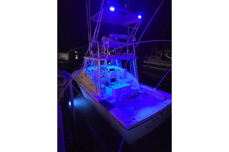 Slide: The Image of 2001 Pursuit 3000 Offshore boat illuminated with blue lights at night. - 7