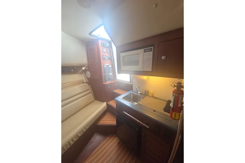 Slide: The Image of Interior of 2001 Pursuit 3000 Offshore boat with kitchenette and seating area. - 14