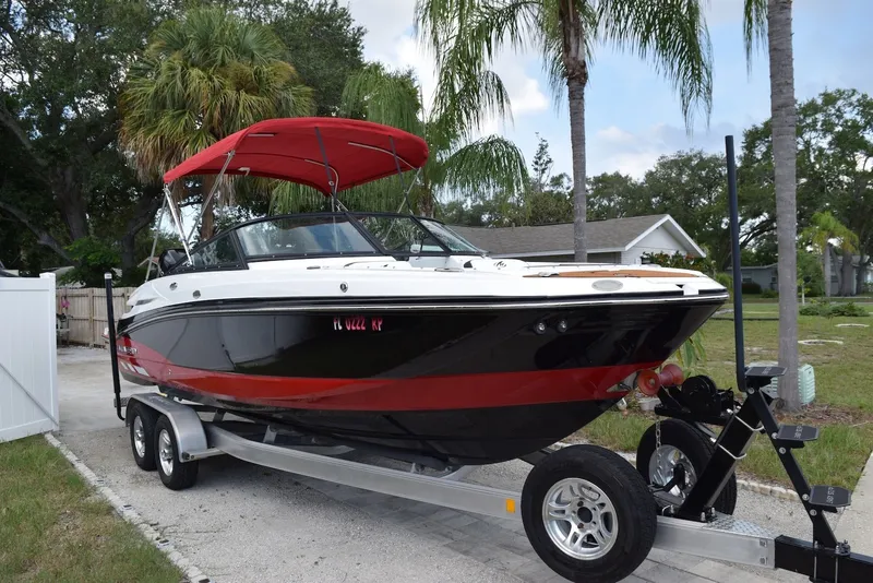 Slide: The Image of 2018 Monterey M-45 boat with red canopy on trailer, parked near palm trees. - 1