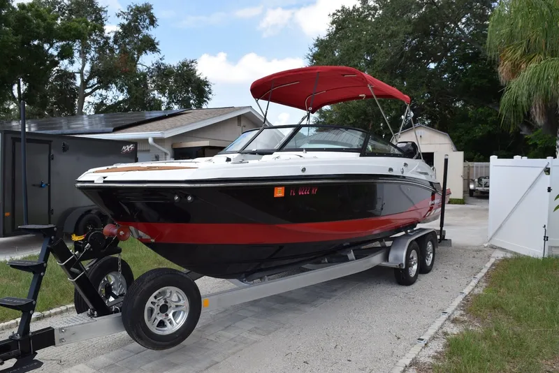 Slide: The Image of 2018 Monterey M-45 boat with red canopy on trailer in driveway. - 2
