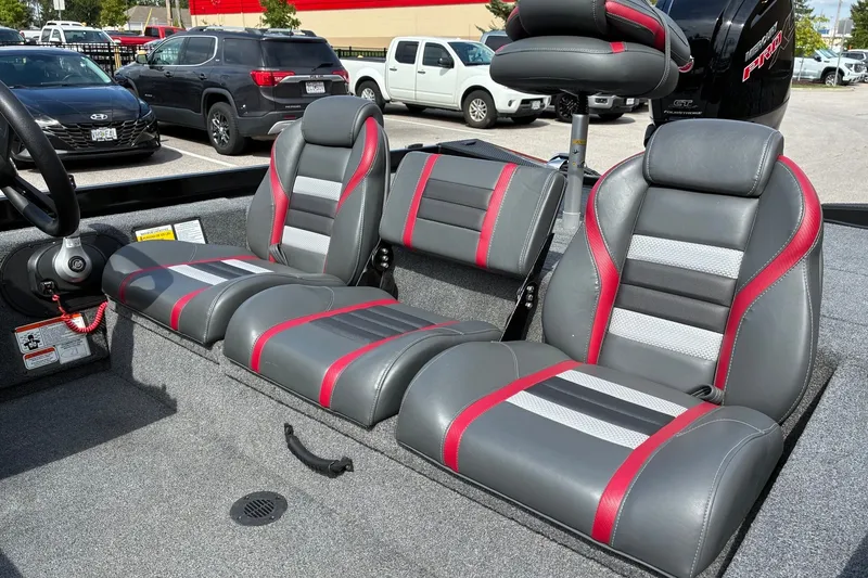 Slide: The Image of 2023 Ranger RT188 boat interior with gray and red seats, parked in a lot. - 11
