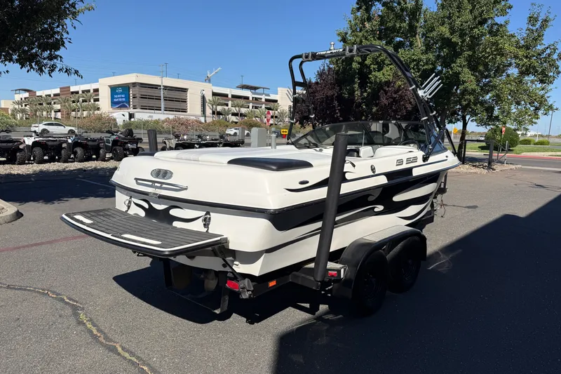 Slide: The Image of 2004 MB B-52 boat on trailer, parked outdoors near trees and buildings. - 5