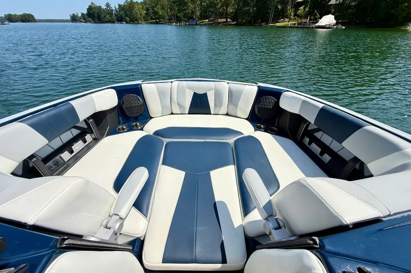 Slide: The Image of 2022 Malibu Wakesetter 23 MXZ boat interior with blue and white seating on a lake. - 20