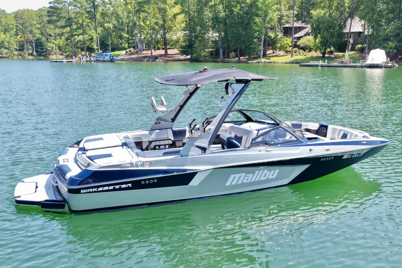 Slide: The Image of 2022 Malibu Wakesetter 23 MXZ boat on a serene lake with lush greenery. - 5