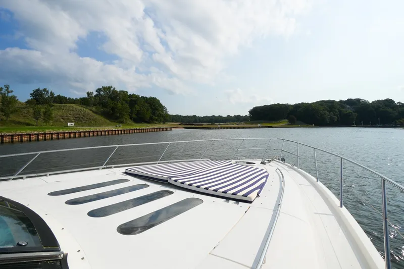 Slide: The Image of 2001 Viking Sport Cruisers V65 yacht cruising on a serene river with lush greenery. - 18