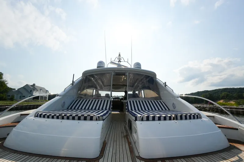 Slide: The Image of 2001 Viking Sport Cruisers V65 yacht with striped sunbeds, docked under a clear sky. - 14