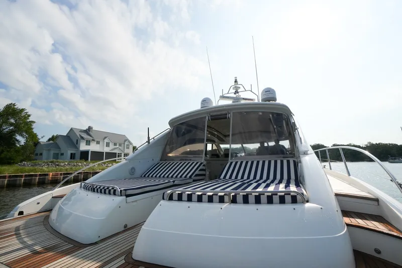 Slide: The Image of 2001 Viking Sport Cruisers V65 yacht with striped sunbeds, docked near waterfront homes. - 15