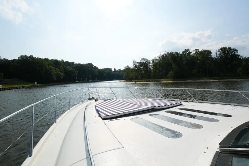 Slide: The Image of 2001 Viking Sport Cruisers V65 yacht cruising on a serene river with lush greenery. - 22