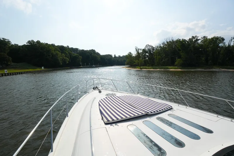 Slide: The Image of Bow view of 2001 Viking Sport Cruisers V65 yacht navigating a serene river. - 27