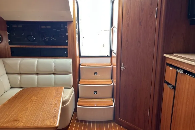 Slide: The Image of Interior of a 1999 Tiara Yachts 3500 Open, featuring wood finishes and a cozy seating area. - 16