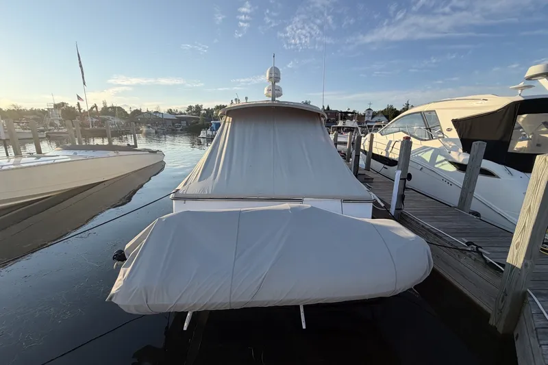 Slide: The Image of 1999 Tiara Yachts 3500 Open docked, covered, with serene marina backdrop. - 6