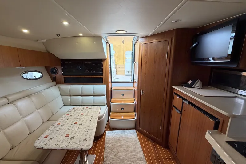 Slide: The Image of Interior of 1999 Tiara Yachts 3500 Open, featuring cozy seating and wooden cabinetry. - 28