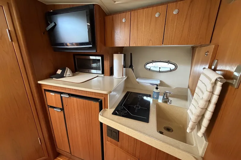 Slide: The Image of 1999 Tiara Yachts 3500 Open galley with stove, sink, fridge, and TV. - 32