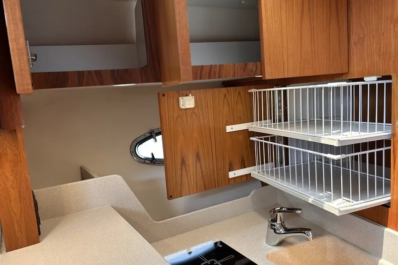 Slide: The Image of 1999 Tiara Yachts 3500 Open kitchen with wooden cabinets and pull-out wire shelves. - 38