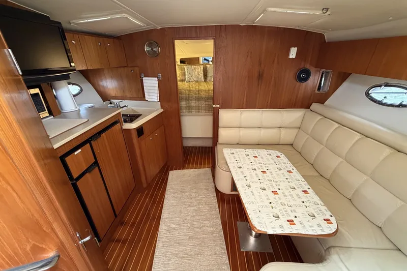 Slide: The Image of 1999 Tiara Yachts 3500 Open interior with kitchenette, seating area, and wood finish. - 27
