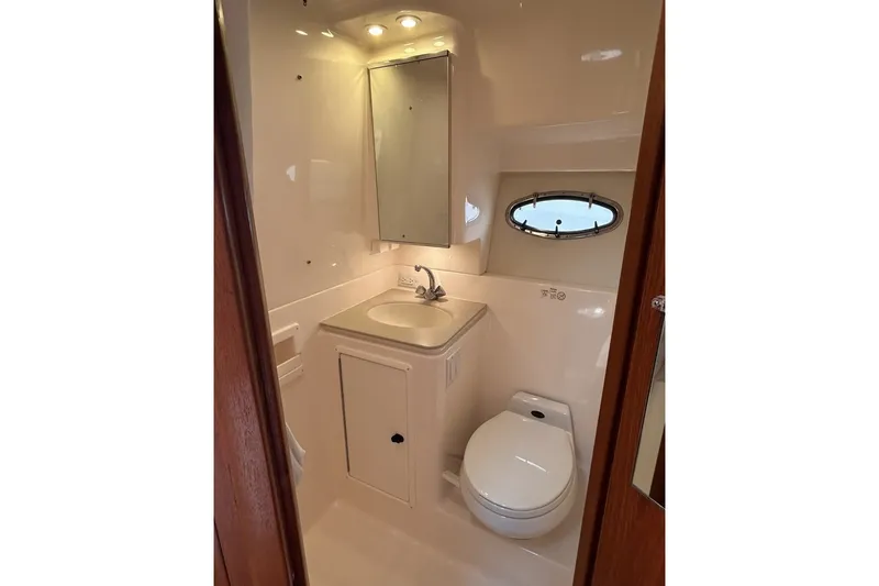 Slide: The Image of Bathroom interior of 1999 Tiara Yachts 3500 Open, featuring sink, toilet, and porthole window. - 35
