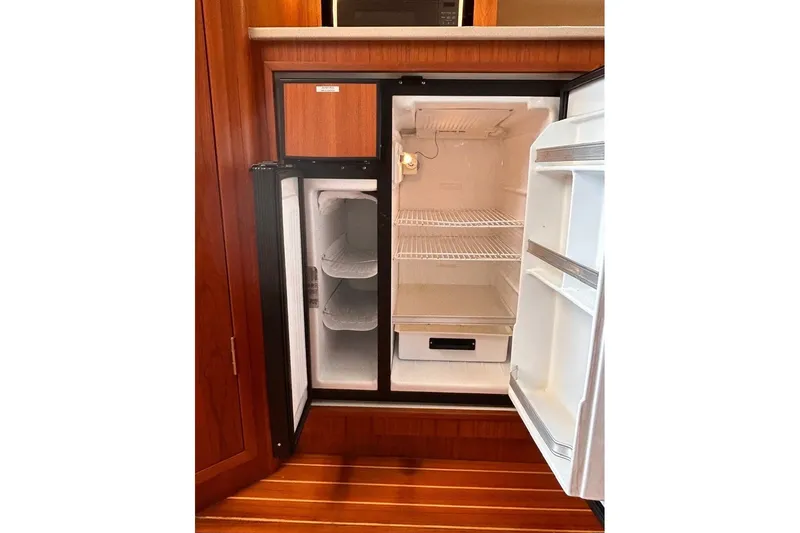 Slide: The Image of 1999 Tiara Yachts 3500 Open refrigerator, open with empty shelves, wooden interior. - 36