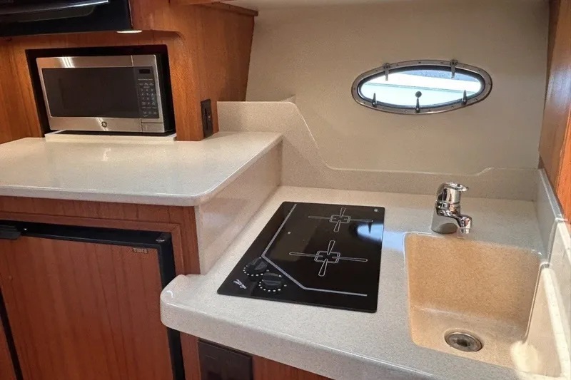 Slide: The Image of 1999 Tiara Yachts 3500 Open galley with microwave, stovetop, sink, and porthole window. - 33