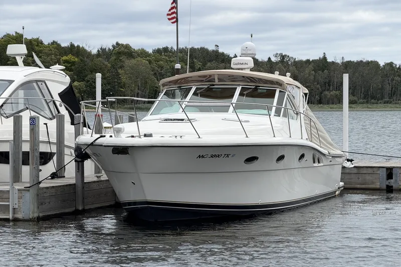 Slide: The Image of 1999 Tiara Yachts 3500 Open docked by a serene lakeside with American flag. - 47