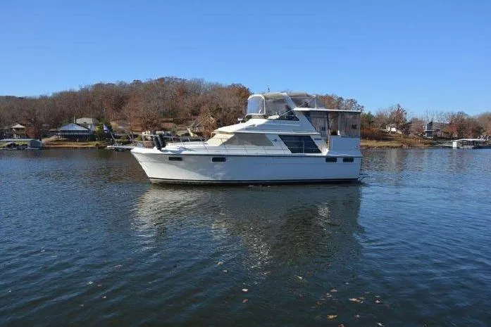 Slide: The Image of 1987 Carver 4207 Aft Cabin Motor Yacht on a serene lake with clear blue sky. - 1