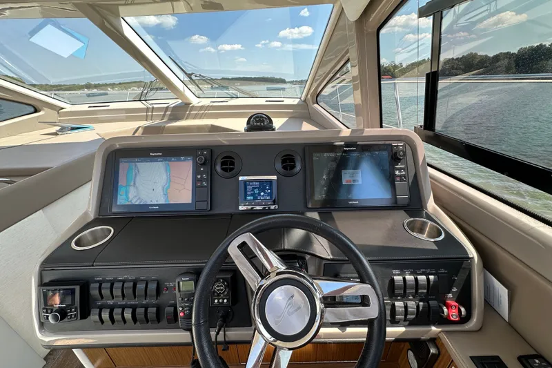 Slide: The Image of 2017 Sea Ray Sundancer 460 helm with navigation screens and steering wheel, overlooking water. - 21