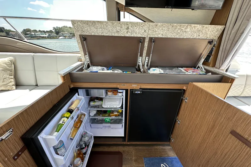 Slide: The Image of 2017 Sea Ray Sundancer 460 yacht interior with open fridge and storage compartments. - 13