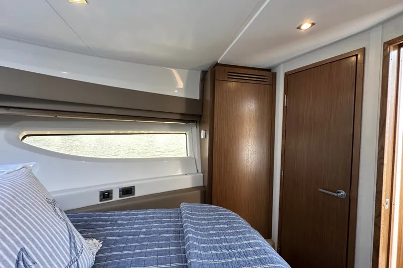 Slide: The Image of 2017 Sea Ray Sundancer 460 cabin interior with bed, window, and wooden door. - 35
