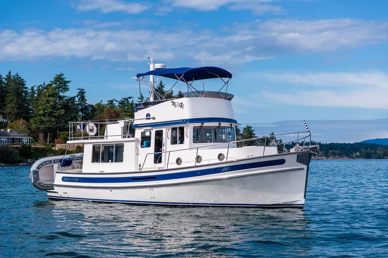 The Image of 2014 Nordic Tug 39 cruising on calm waters with scenic forested shoreline. - 0
