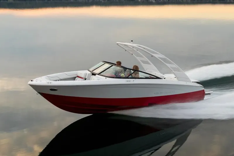 Slide: The Image of Manufacturer Provided Image: 2026 Regal LS2 Surf boat gliding swiftly on calm water at sunset. - 2