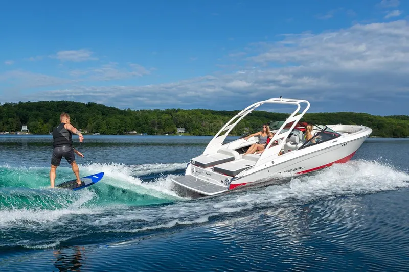Slide: The Image of Manufacturer Provided Image: 2026 Regal LS2 Surf boat on lake, towing a wakeboarder, with passengers enjoying the ride. - 5