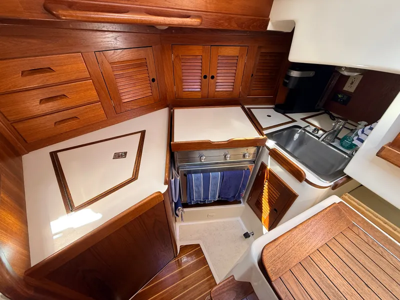 Slide: The Image of The galley of a 1992 Tartan T 31 with wooden cabinets and a stainless steel sink. - 15