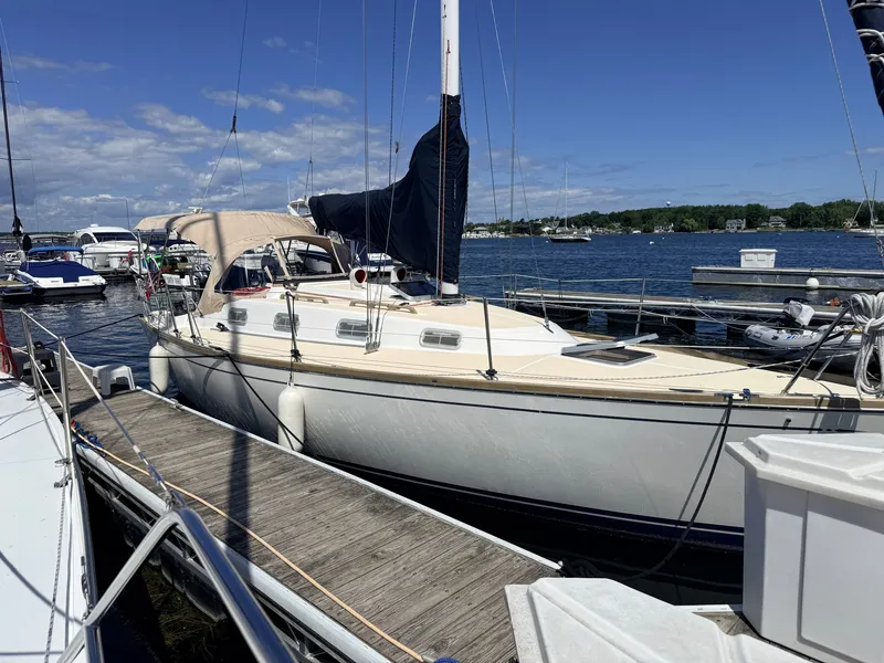Slide: The Image of A 1992 Tartan T 31 docked, featuring a beige canopy and sails. - 2