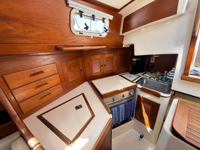 Slide: The Image of Interior of a 1992 Tartan T 31 with wooden cabinets and a small kitchen area. - 16